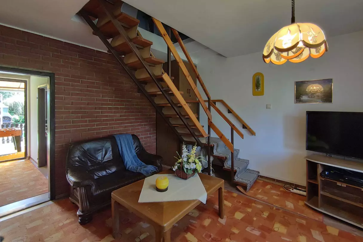A képen, a földszinti nappali látható a tetőtérbe felvezető lépcsővel
