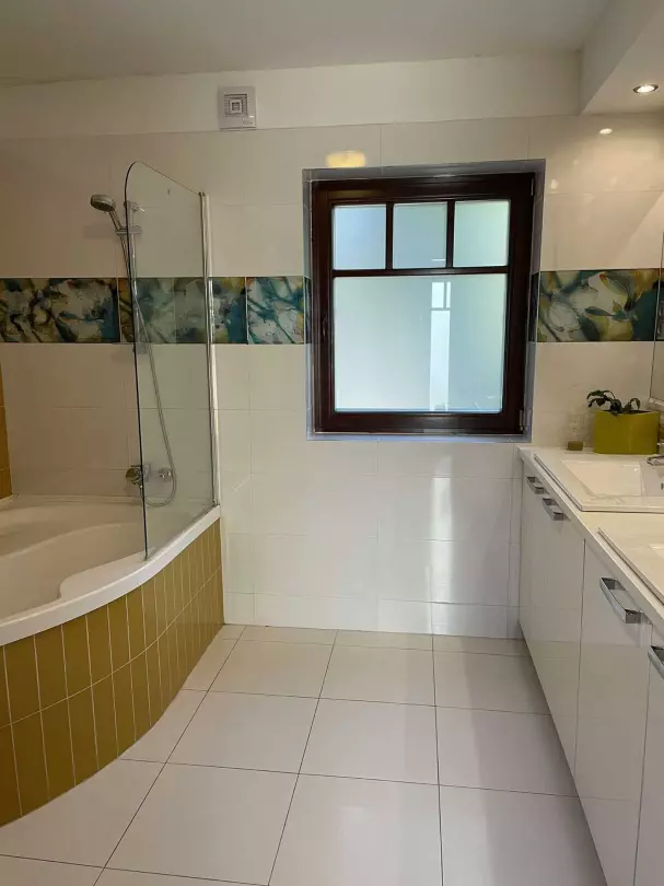 A képen, a folyosó végén lévő fürdőszoba (kétállásos mosdó és zuhanyozó) látható