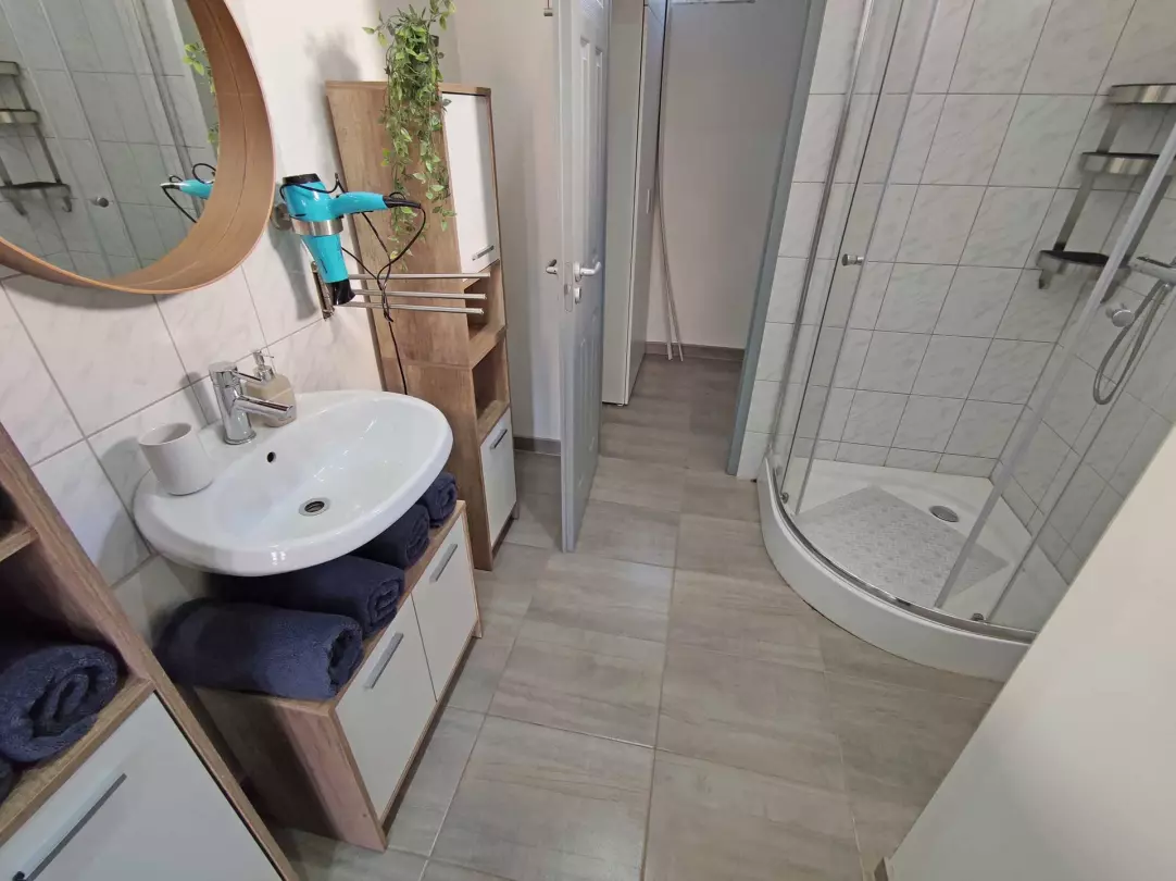 A képen, a földszinti fürdőszoba (zuhanyozó,- mosdó) látható. A fürdőszobából nyílik a háztartási helyiség, itt található a mosógép és a villanybojler. 