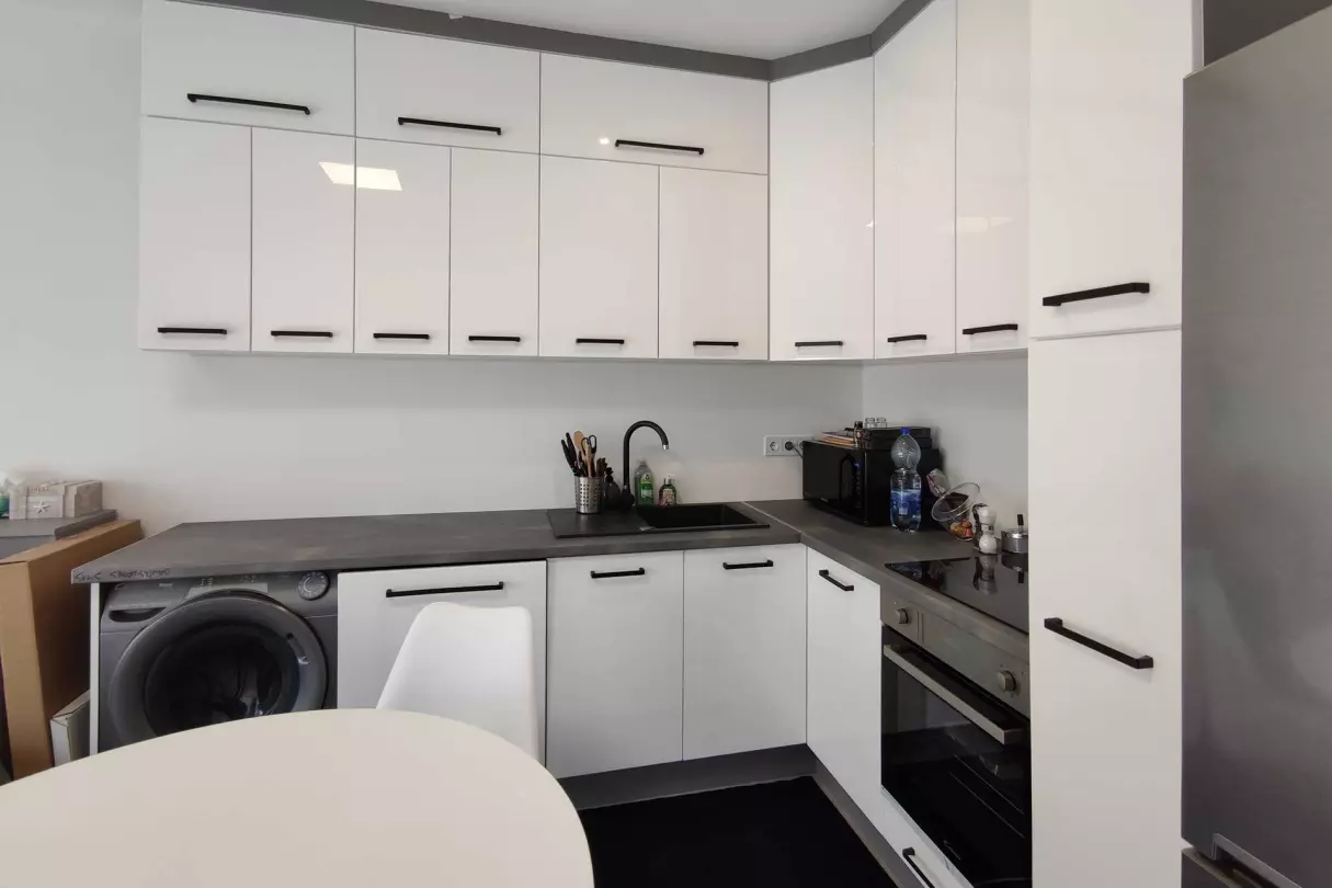 A képen, a konyha látható, melybe be van építve az indukciós főzőlap, a sütő, az automata mosogatógép és az automata mosógép