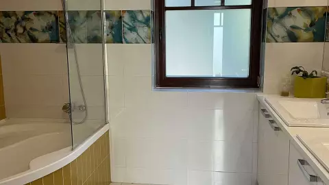A képen, a folyosó végén lévő fürdőszoba (kétállásos mosdó és zuhanyozó) látható