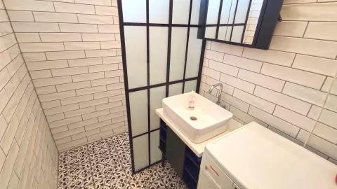 Az ablakkal rendelkező fürdőszoba berendezési tárgyai: zuhanyozó és mosdó
